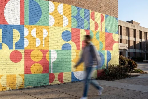 Colorful geometric mural painted on a university brick wall, designed for Western Washington University Student Publications.